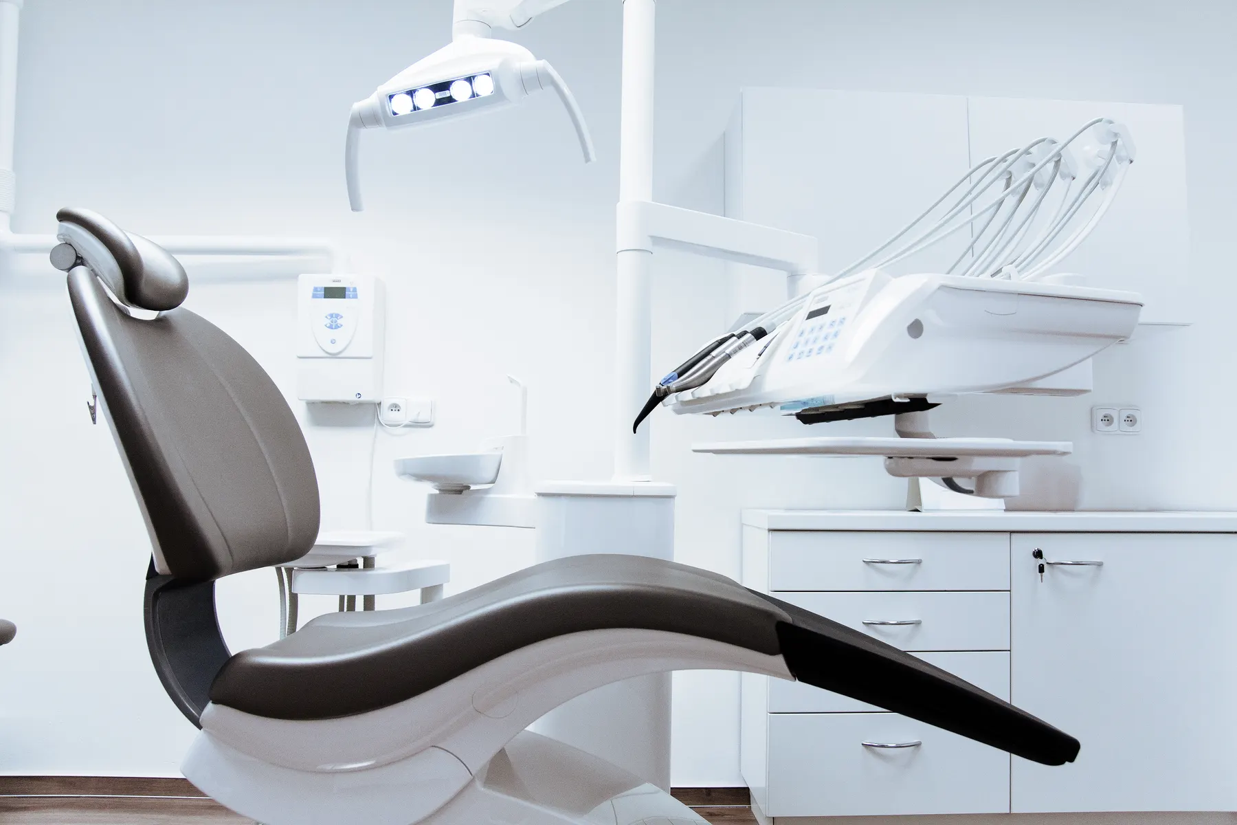 A bright, white dental treatment room with a clean chair and overhead light