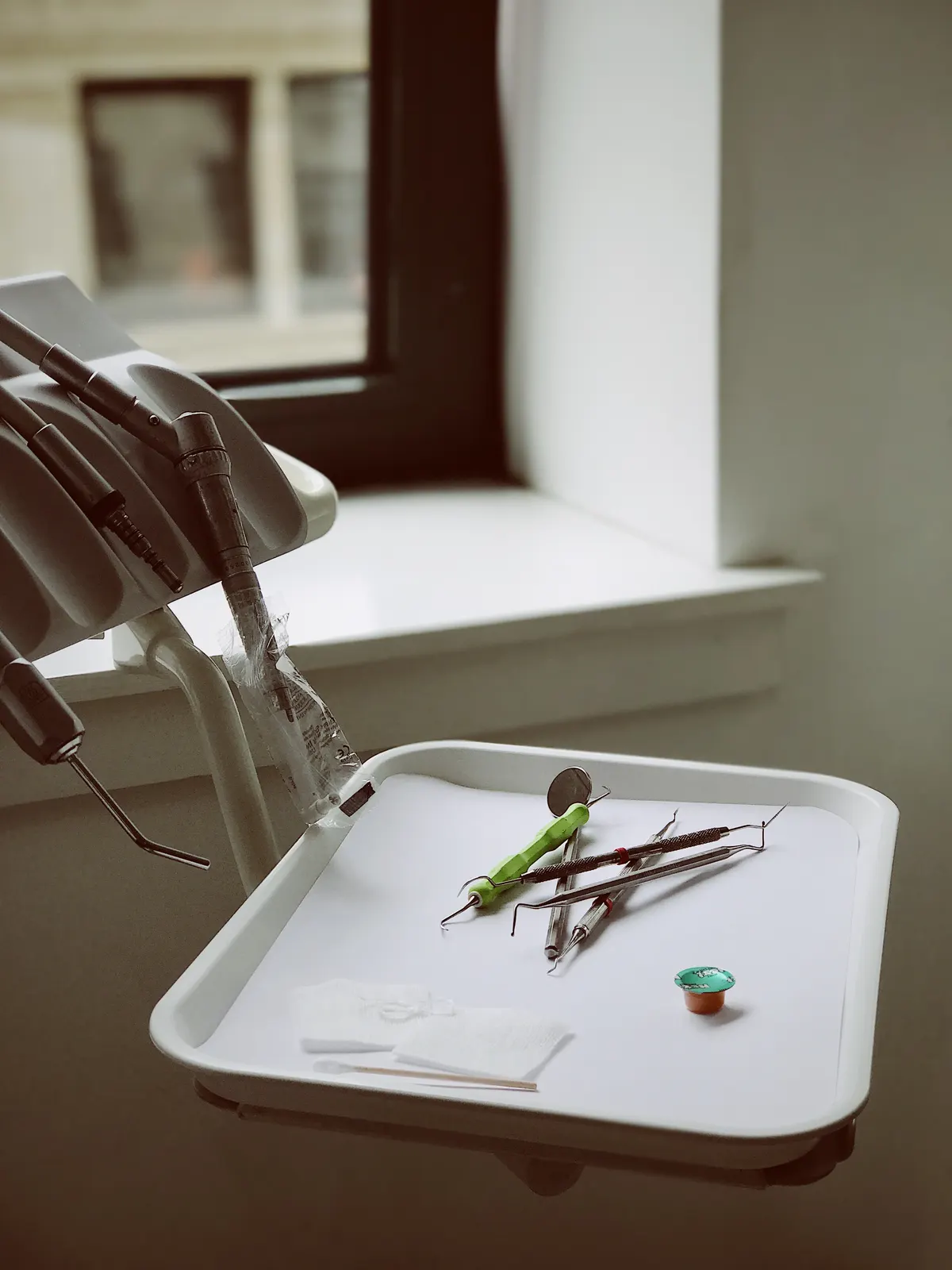A clean instrument tray beside a treatment chair with daylight from a window